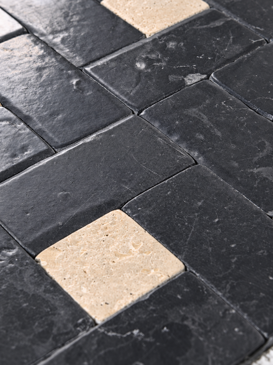 Black stone mosaic tile sheet with alternating square black tiles and smaller beige accent tiles.