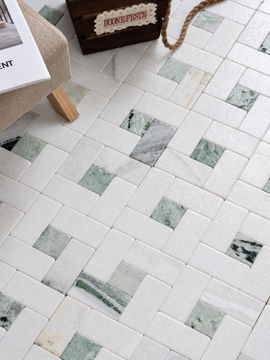 White and green marble mosaic floor tiles arranged in a basketweave pattern, shown in a styled interior setting with part of a chair and a decorative box visible.