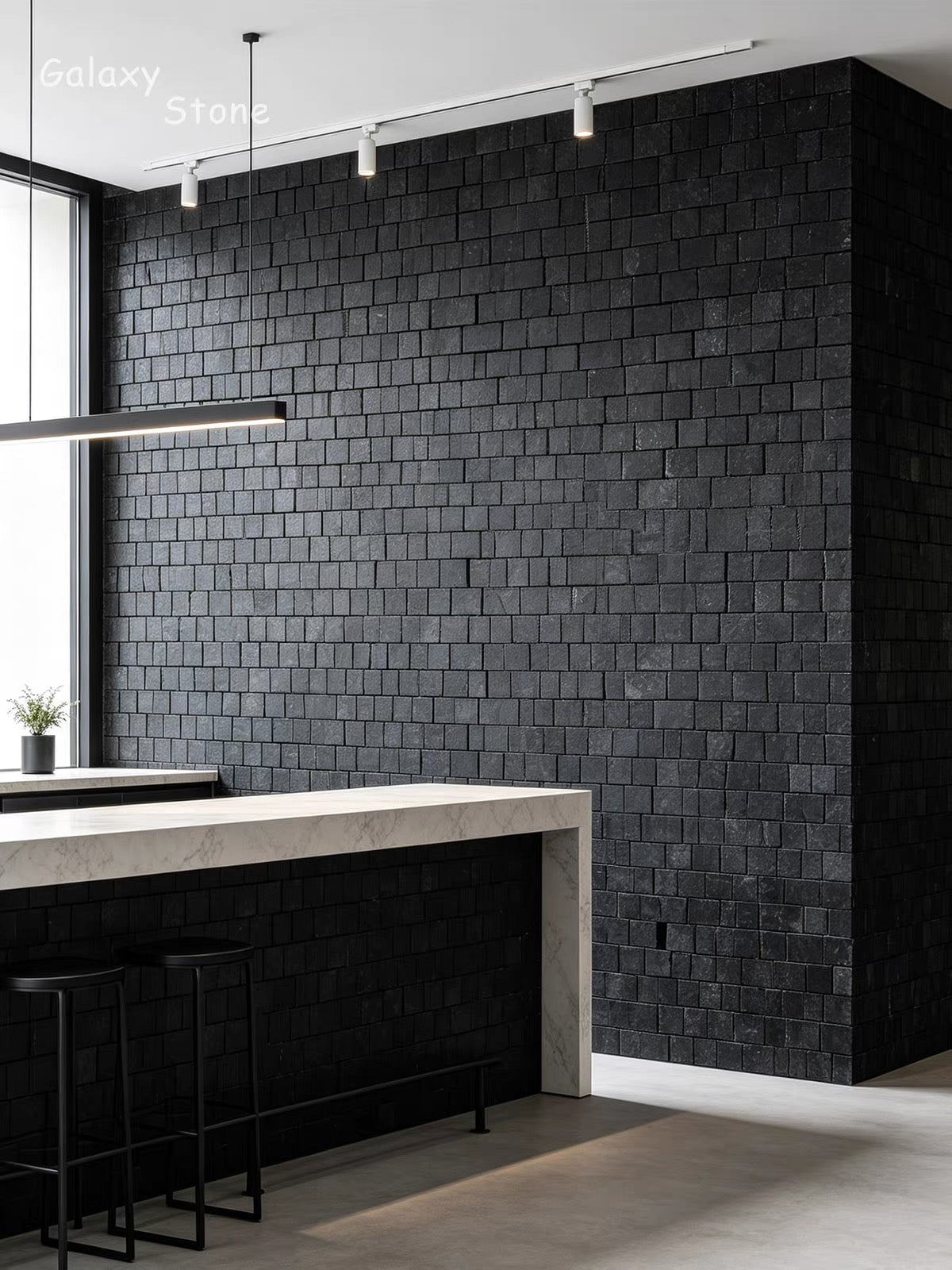 A modern kitchen interior featuring a prominent black brick-style wall backsplash and matching black tiled island base, with a light stone countertop and black bar stools.
