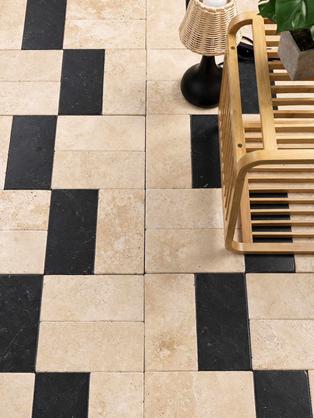 Beige and black checkered stone floor tiles shown in a styled interior scene with a wooden bench, lamp, and plant.